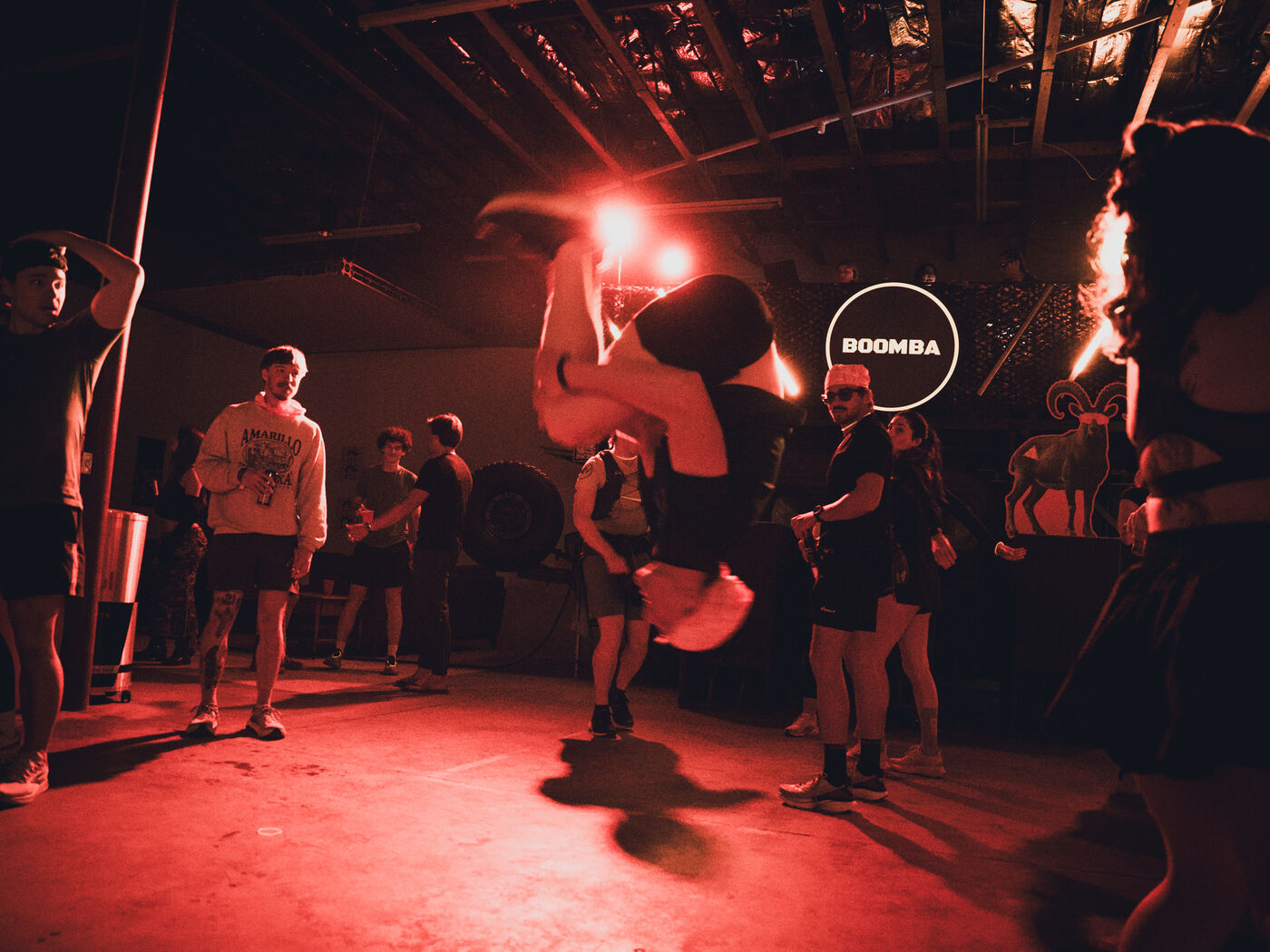 Breakdancer mid-flip under red light at a BOOMBA event