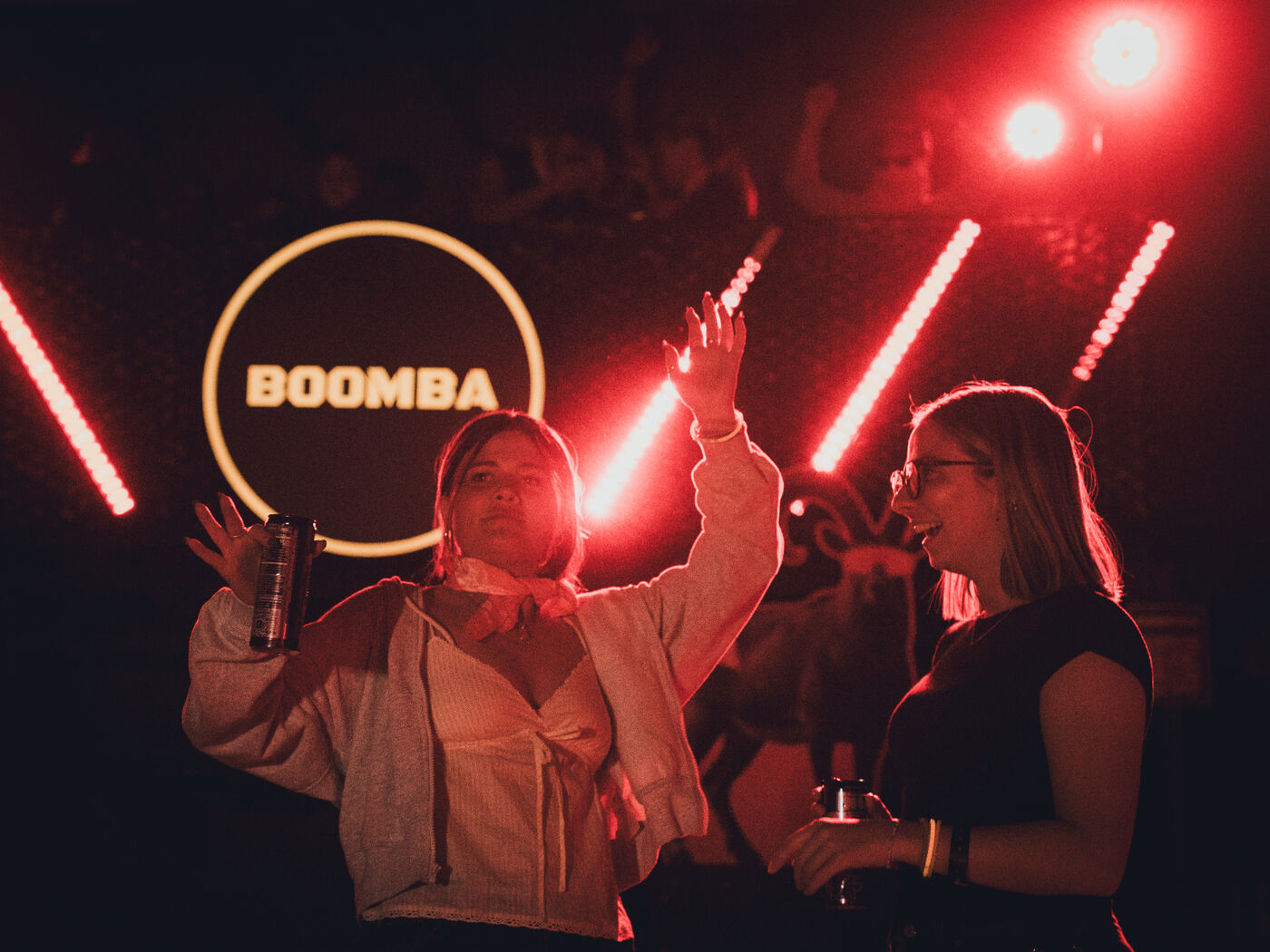 Dancers under red light tubes with the glowing BOOMBA sign