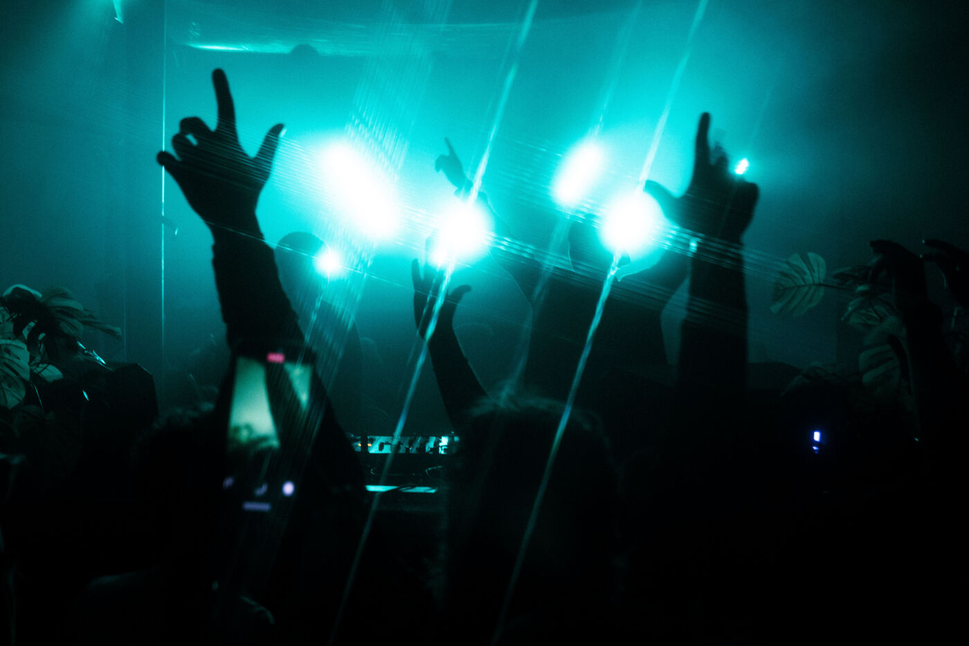 Hands up in teal light at a BOOMBA warehouse show