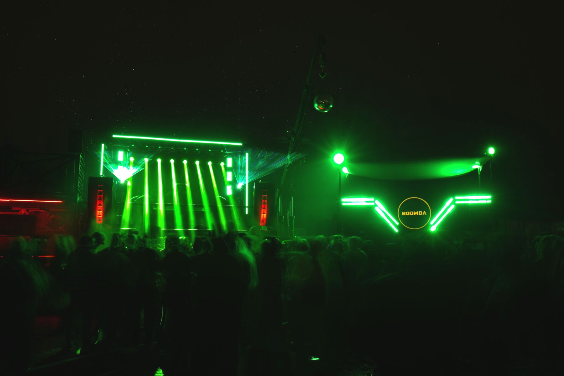 Green lasers fanning over a night crowd at a BOOMBA show